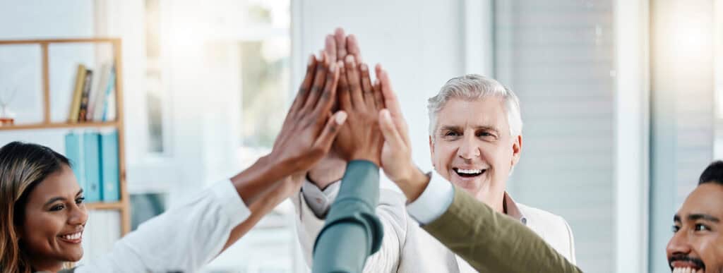 En grupp i ledarskapsutveckling håller upp händerna i en gemensam high five